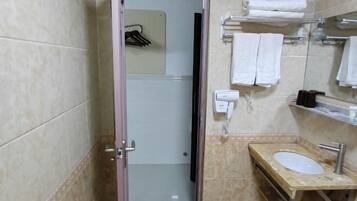 Ein Badezimmer mit Waschbecken, Spiegel, Handtuchhalter und Duschbereich.