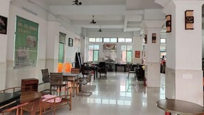A spacious hotel lobby with high ceilings, multiple seating areas, and large windows allowing natural light. - longzhou hostel (Wanning)