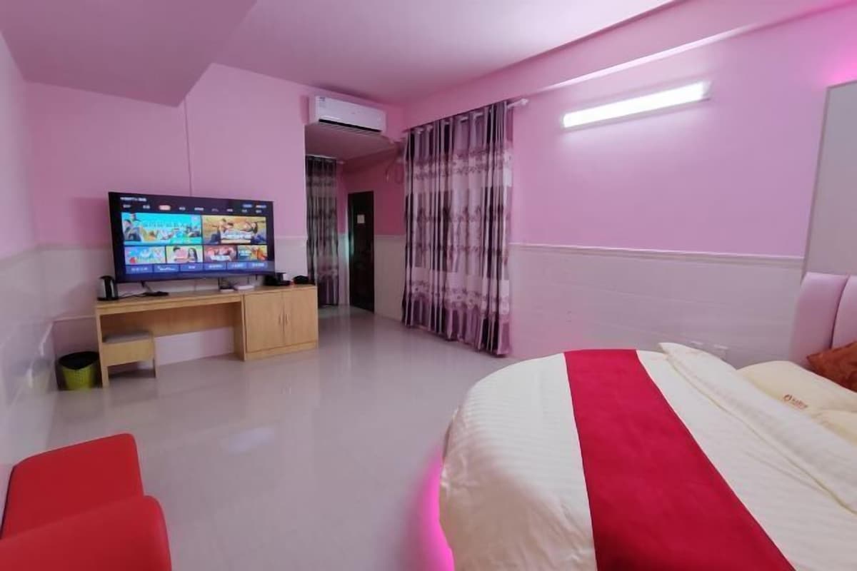 A bedroom with a bed, a TV, a desk, and a chair.