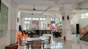 A spacious, well-lit room with high ceilings, large windows, and a variety of seating arrangements including tables and chairs. - longzhou hostel (Wanning)