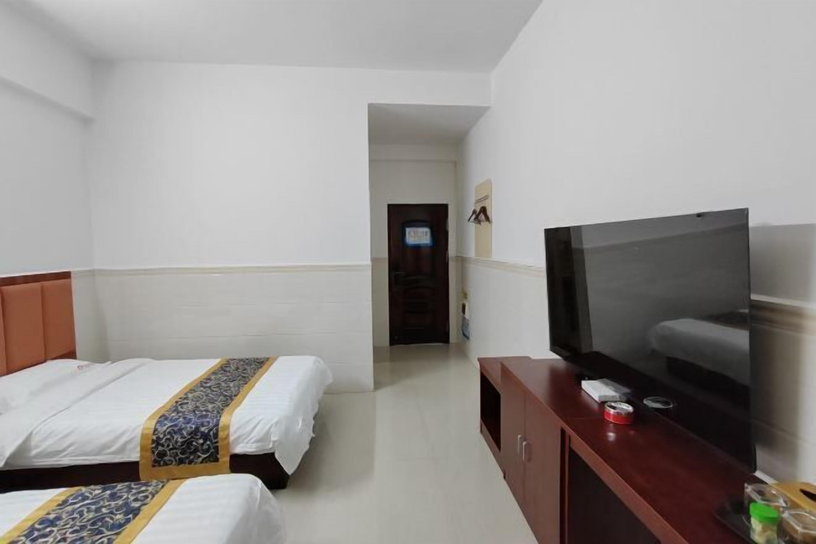 Een hotelkamer met twee bedden, een televisie en een houten kast.