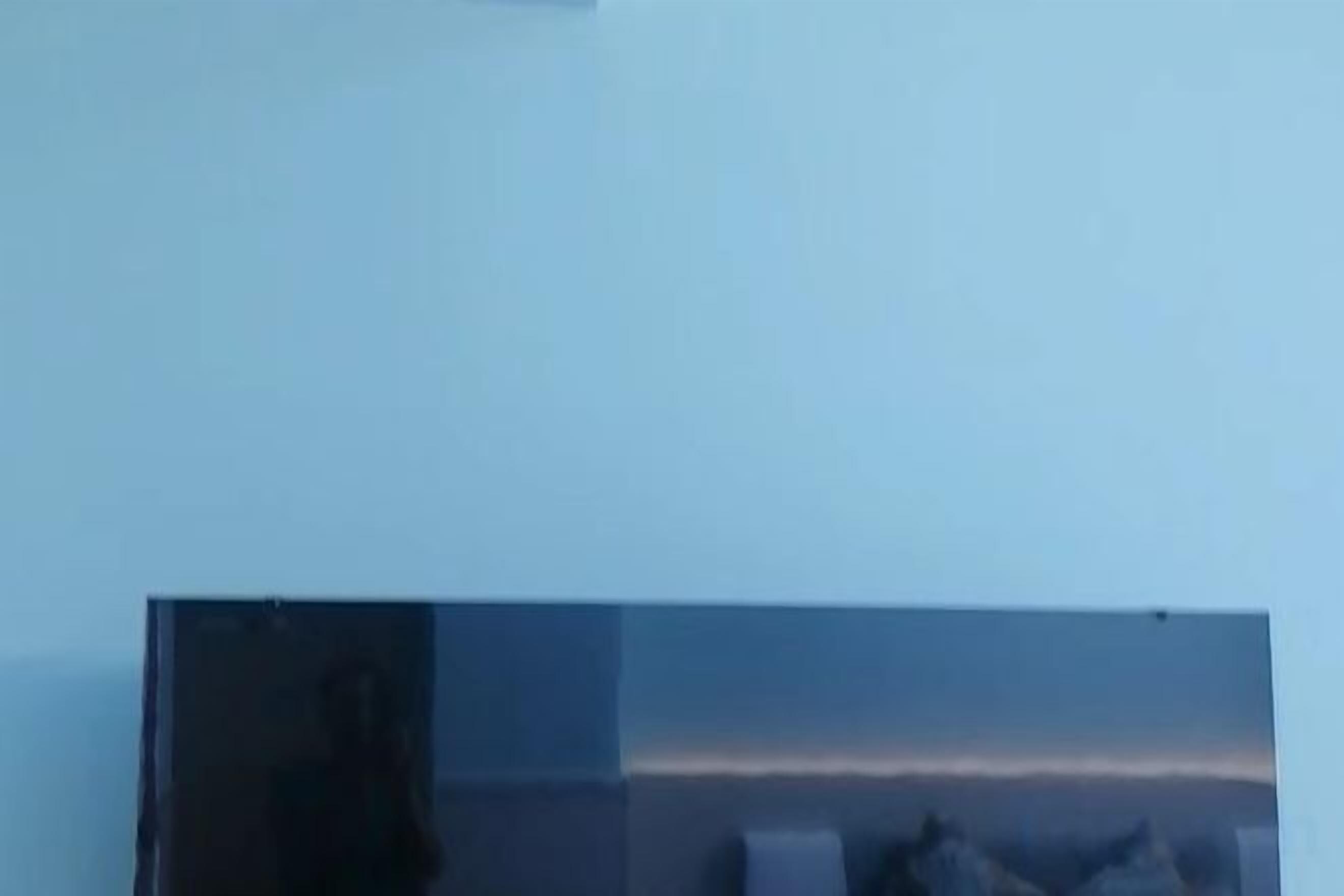 A room with a large window, a flat-screen TV, and a bed.