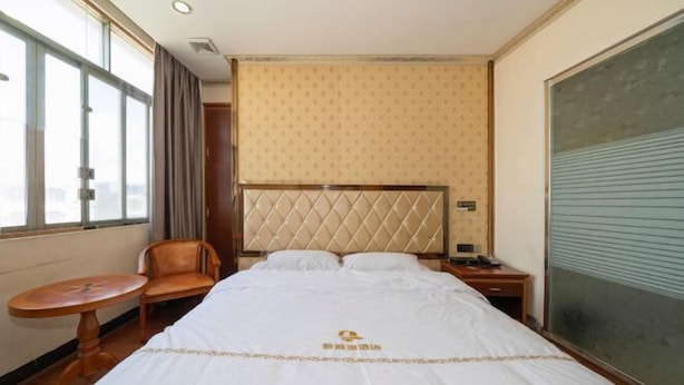 Hotellihuone, jossa on sänky, tuoli, pieni pöytä ja ikkuna.