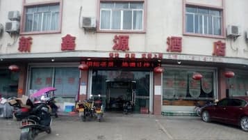A hotel with a signboard, a storefront, and a parking area with vehicles.
