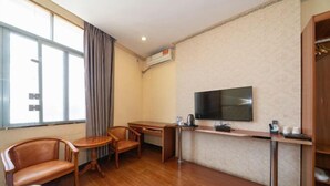 Hotellihuone, jossa on sänky, työpöytä, tuoli, televisio ja vaatekaappi.