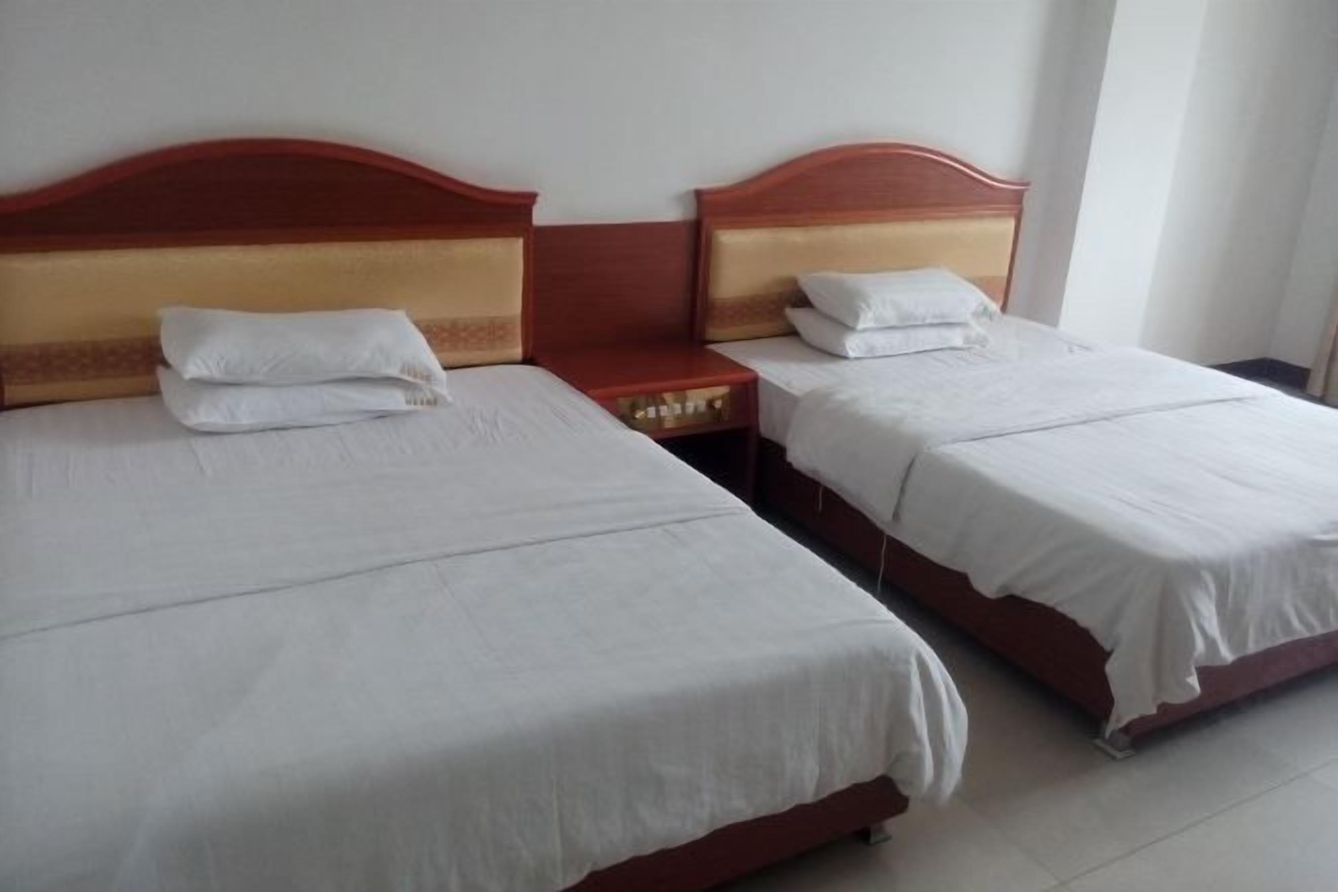 Two single beds with wooden headboards and white bedding in a hotel room.