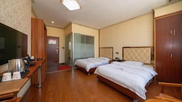 A hotel room with two beds, a desk with a flat-screen TV, a wardrobe, and a shower area.