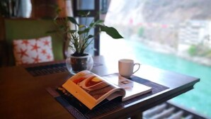 Una mesa con una revista, una taza y una planta en maceta.
