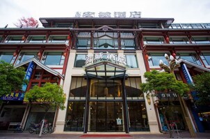 A hotel with a traditional architectural style, featuring a prominent entrance with glass doors and a red carpet leading to the lobby.