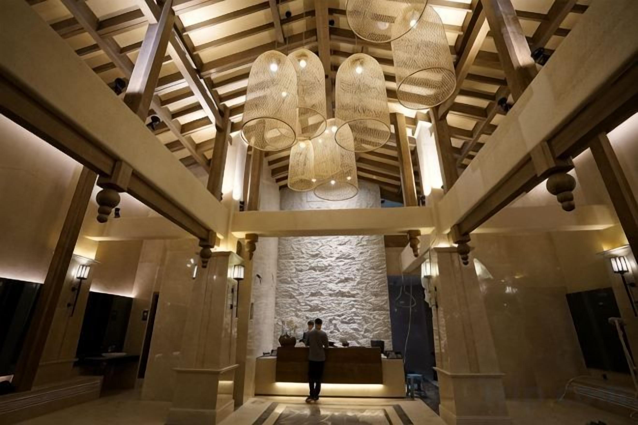 Un vestíbulo con techo alto, un mostrador de recepción y una pared de piedra.