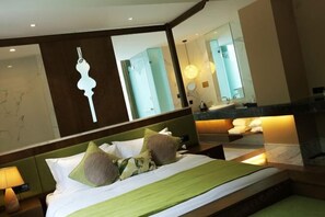 Una habitación de hotel con cama, mesita de noche, espejo y baño con lavabo y espejo.