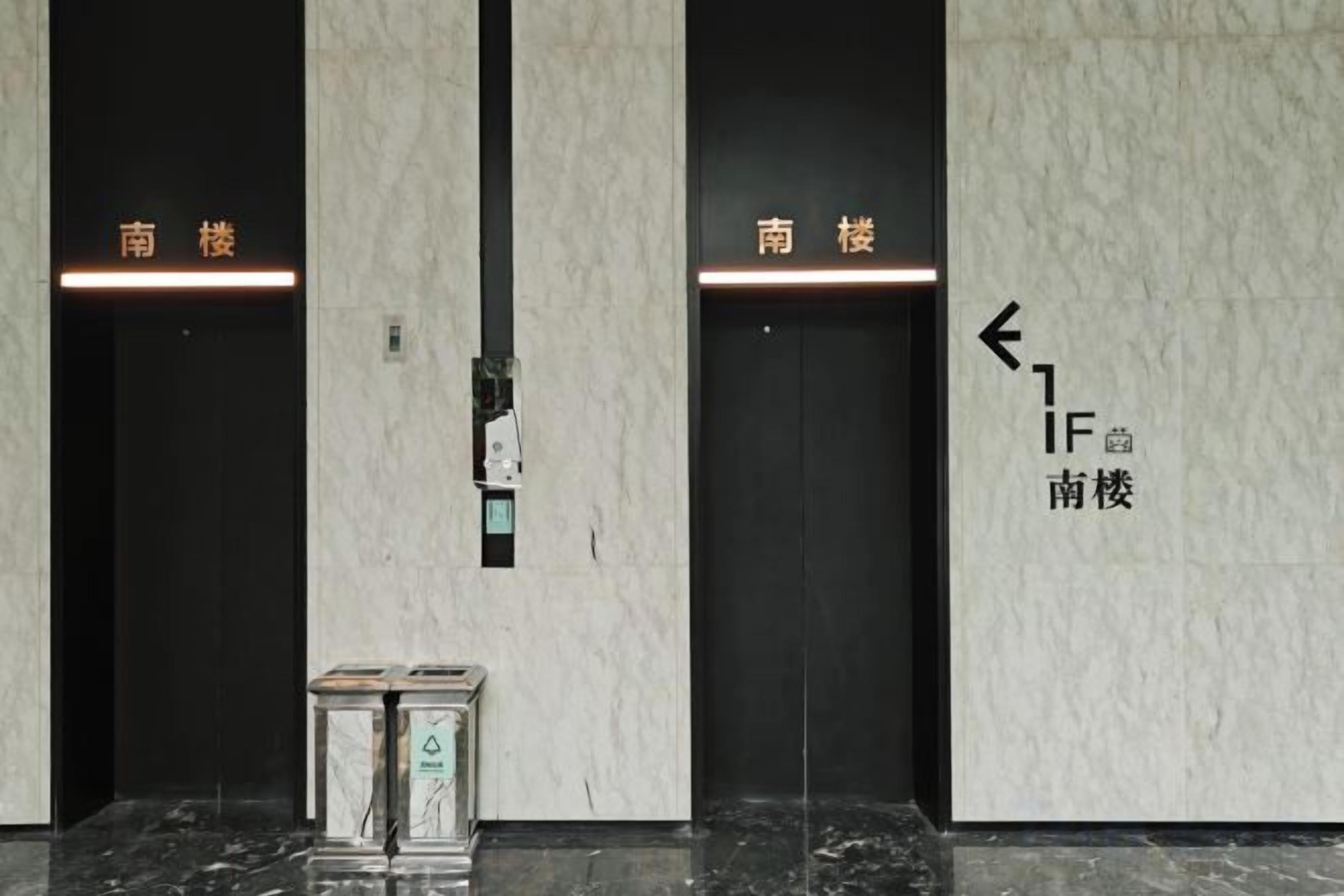 Two elevator doors with directional arrows and the text 'IF' and '南楼' indicating the direction to the south floor.