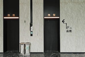 Deux portes d’ascenseur, chacune ornée de flèches indiquant la direction et du texte « IF » et « 南楼 », qui indiquent la direction à prendre pour accéder au rez-de-chaussée sud.