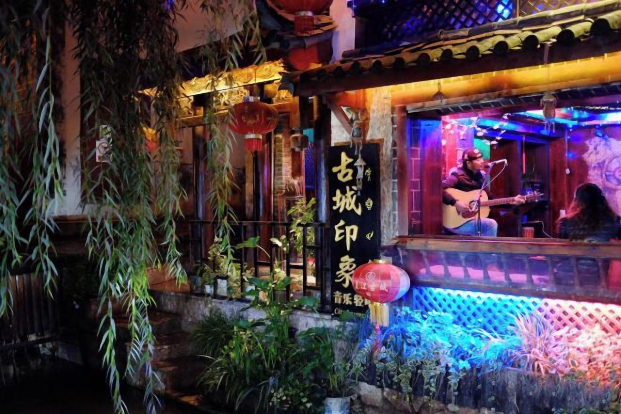 A traditional building with a sign, a person playing guitar, and decorative plants.