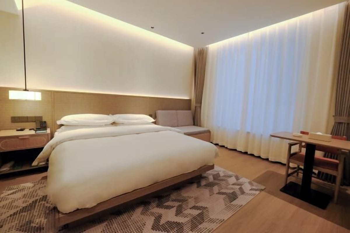 Una habitación de hotel moderna con una cama grande, mesitas de noche, un escritorio y una silla.