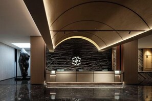 A reception area with a stone wall, a star-shaped light fixture, and a polished floor. - JP Hyllis Hotel (Lijiang)