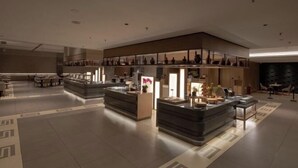 En moderne hotellobby med et centralt receptionsområde, siddepladser og dekorative genstande.