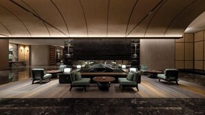 En moderne lobby med et centralt siddeområde, en stenvæg og et træloft.