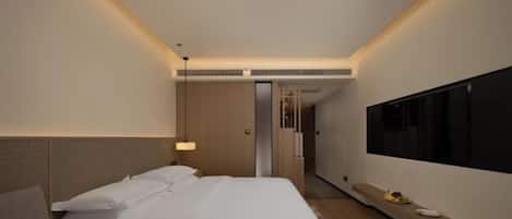 A modern hotel room with a large bed, a TV, and a small desk.