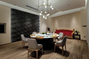 A modern dining area with a round table, chairs, and a chandelier. - JP Hyllis Hotel (Lijiang)