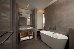 Un baño moderno con una bañera independiente, un espejo grande y un tocador con encimera de mármol.