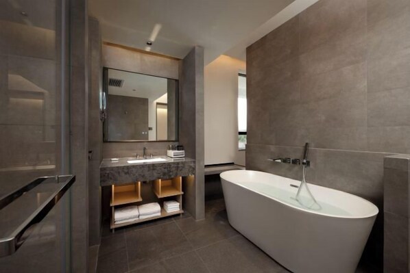 A modern bathroom with a freestanding bathtub, a large mirror, and a vanity with a marble countertop. - JP Hyllis Hotel (Lijiang)