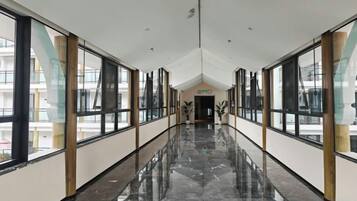 A long, narrow hallway with large windows on both sides, leading to a door at the end.
