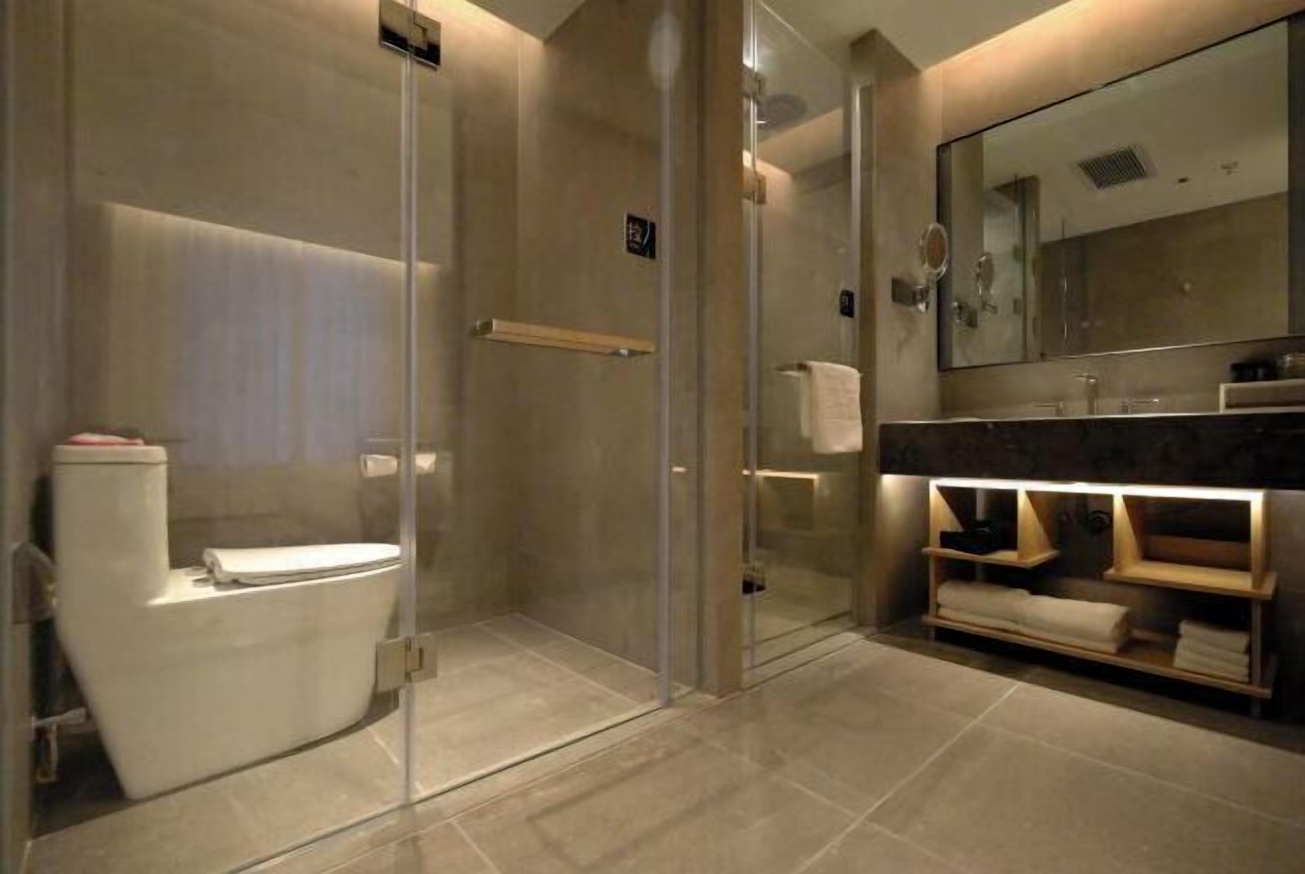 A modern bathroom with a glass-enclosed shower, a toilet, and a vanity with a mirror and towel rack.