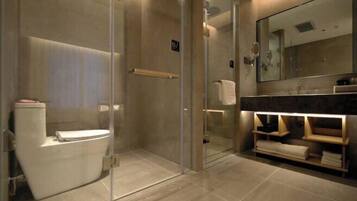 A modern bathroom with a glass-enclosed shower, a toilet, and a vanity with a mirror and towel rack.