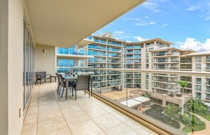 A balcony with a table and chairs, overlooking a residential building with multiple balconies.