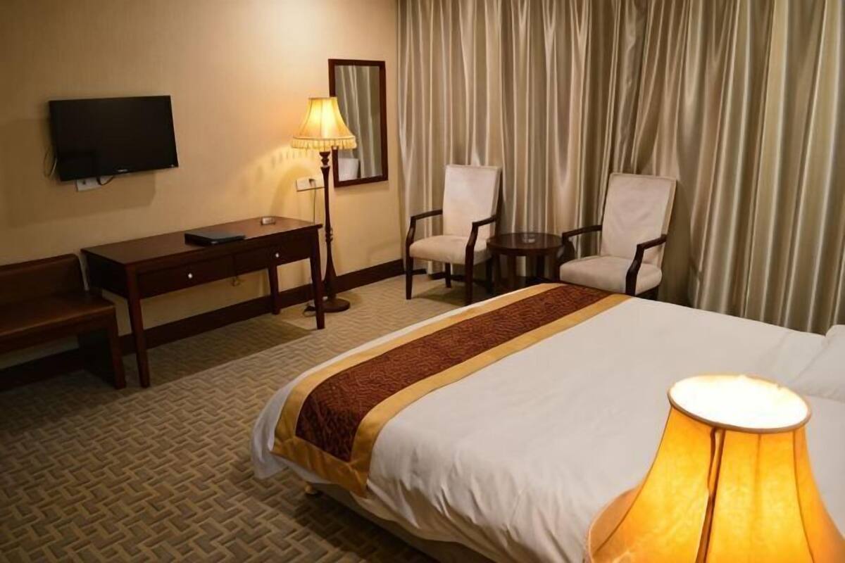 Una habitación de hotel con una cama, un escritorio, una silla, un televisor y una lámpara.