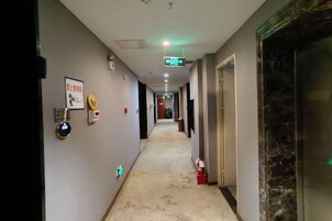 Un pasillo de hotel con piso alfombrado, un extintor y una puerta a la derecha.