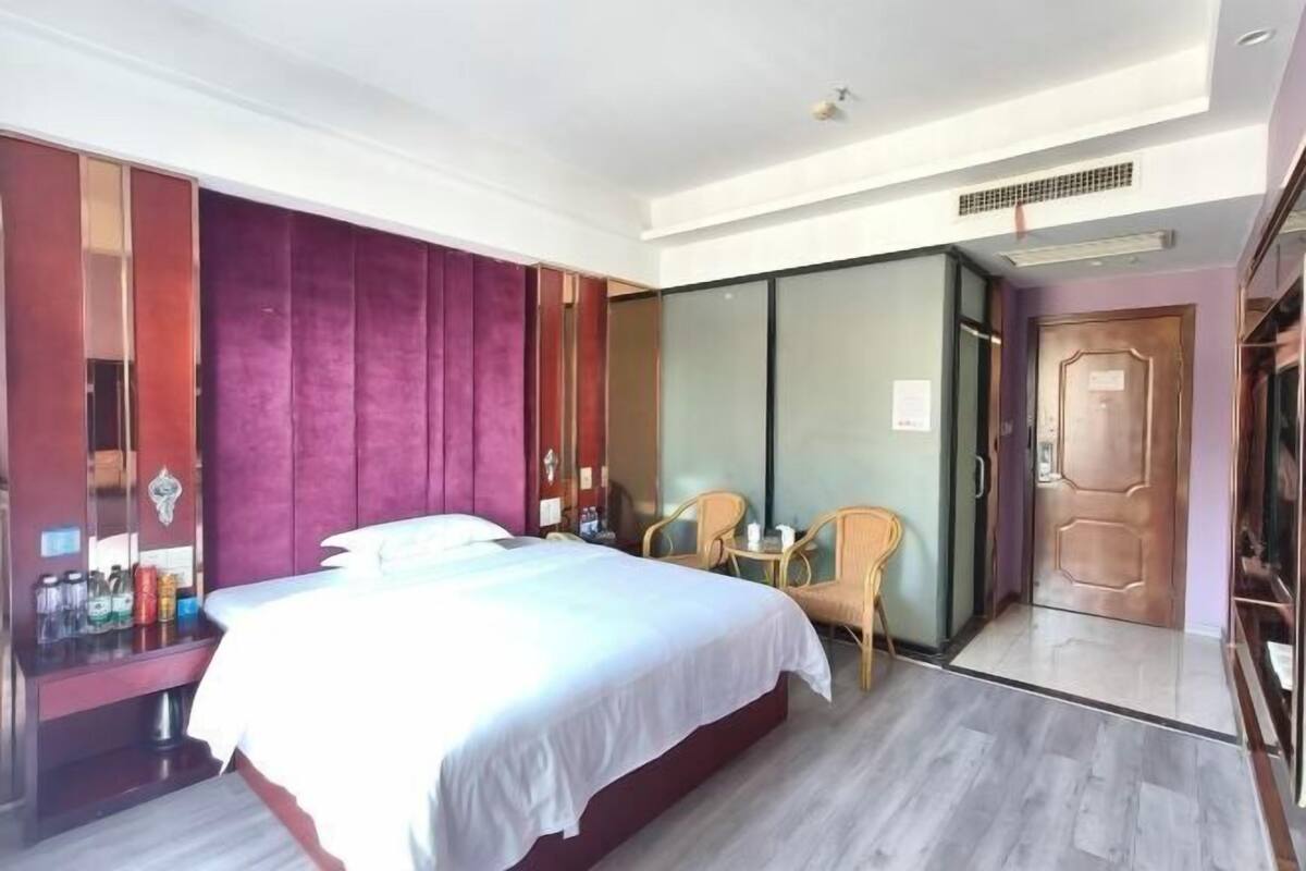 Een hotelkamer met een bed, een zithoek met stoelen, een kledingkast en een deur.