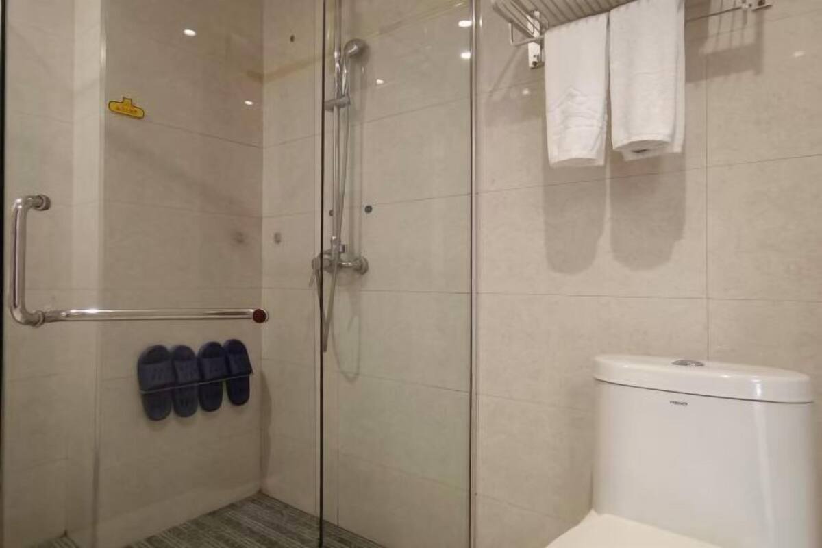 Een badkamer met een douchecabine van glas, een wit toilet en een handdoekrek met handdoeken.
