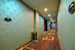 Pasillo de hotel con paredes con diseño, piso alfombrado y un letrero que indica la habitación 8510.