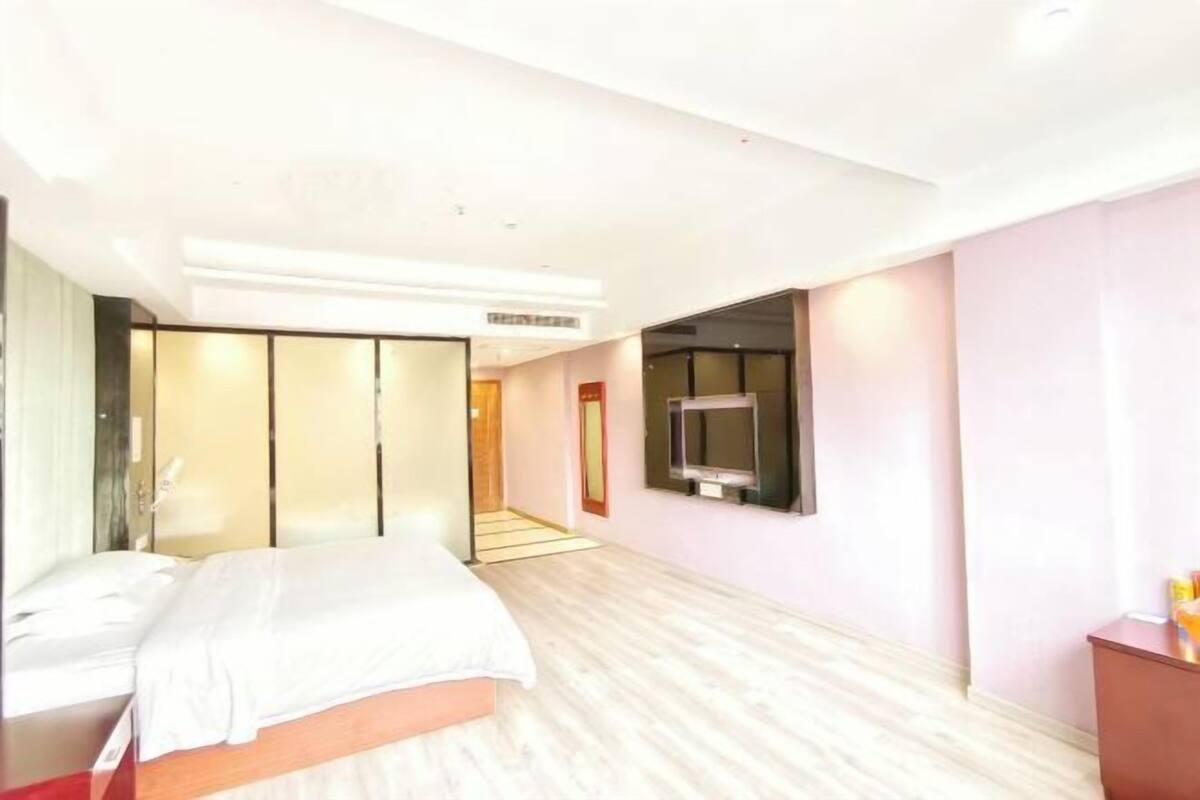 Een hotelkamer met een bed, een aan de muur bevestigde televisie en een schuifdeurkast.