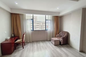 Una habitación con un ventanal grande, un escritorio, una silla y un sofá.