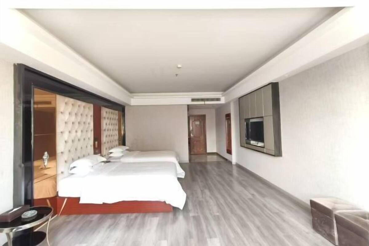 Een hotelkamer met een groot bed, een aan de muur bevestigde televisie en een aparte zithoek.