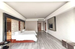 Ein Hotelzimmer mit einem großen Bett, einem an der Wand befestigten Fernseher und einer separaten Sitzecke.