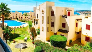 Un resort con piscina, palmeras y edificios de estilo mediterráneo.