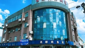 A multi-story building with a curved glass facade, signage for 'Nanjing Business Center', and a blue awning with 'Nanjing Business Center' written on it. - Shaoxing Mingdu Business Hotel (Shaoxing)
