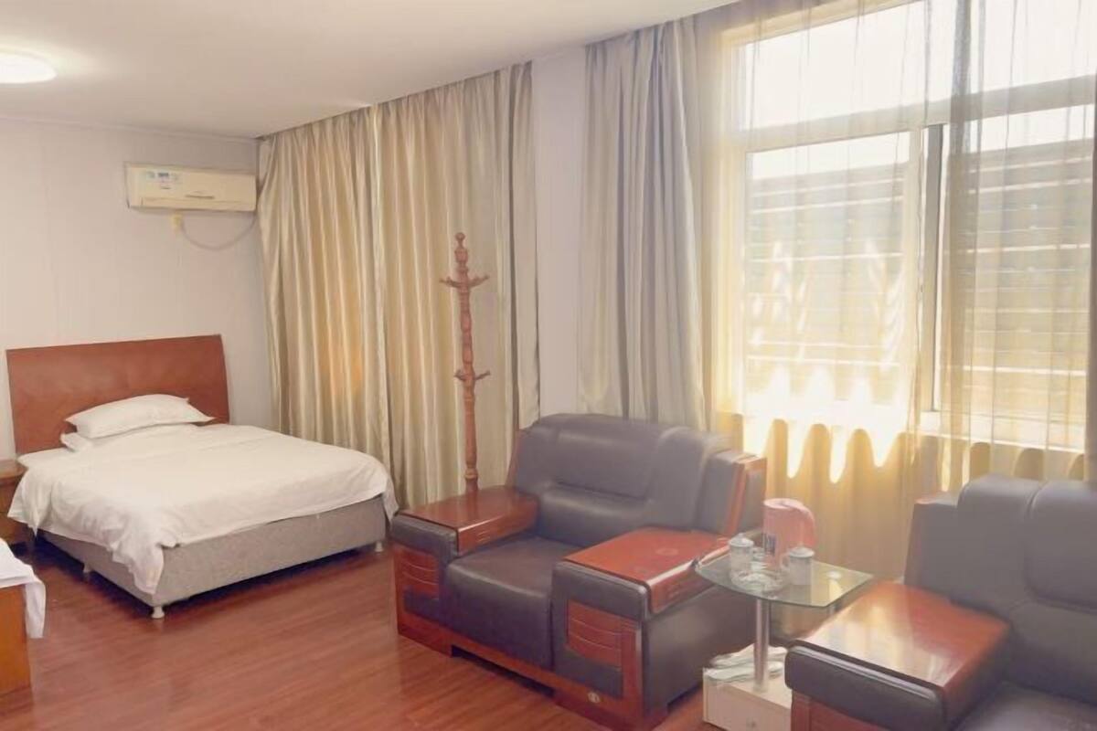 A hotel room with a bed, a sofa, a small table, and curtains.