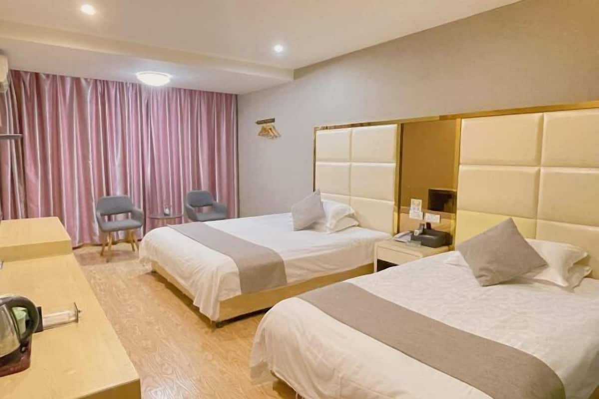Una habitación de hotel con dos camas, un escritorio, una silla y un espejo grande.