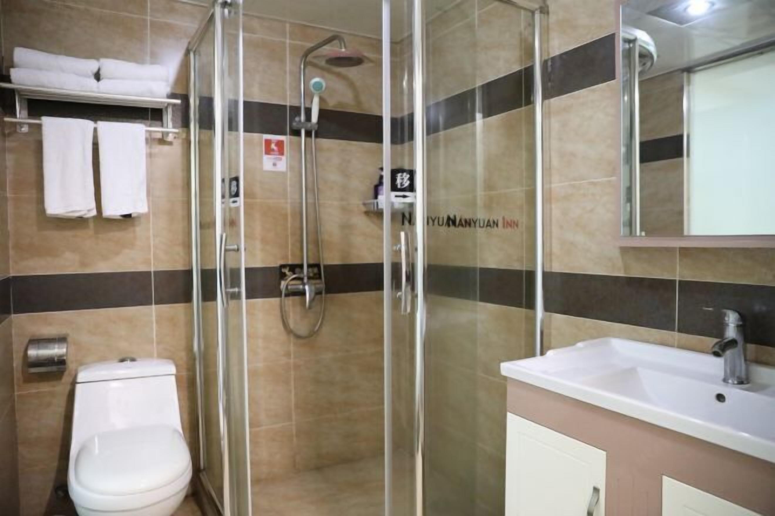 Een moderne badkamer met een douchecabine van glas, een wit toilet en een wastafel met spiegel.