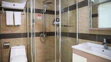 Een moderne badkamer met een douchecabine van glas, een wit toilet en een wastafel met spiegel.