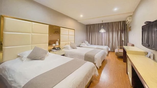 Ein Hotelzimmer mit zwei Betten, einem Schreibtisch und einem Fernseher.
