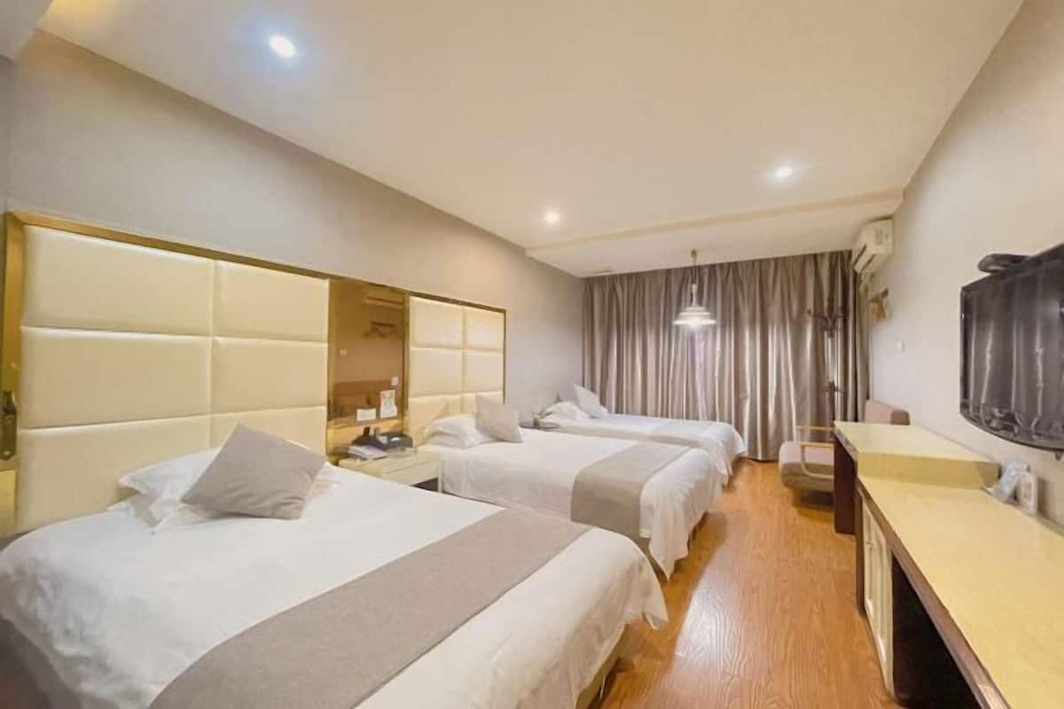 Habitación de hotel con dos camas, un escritorio y un televisor.