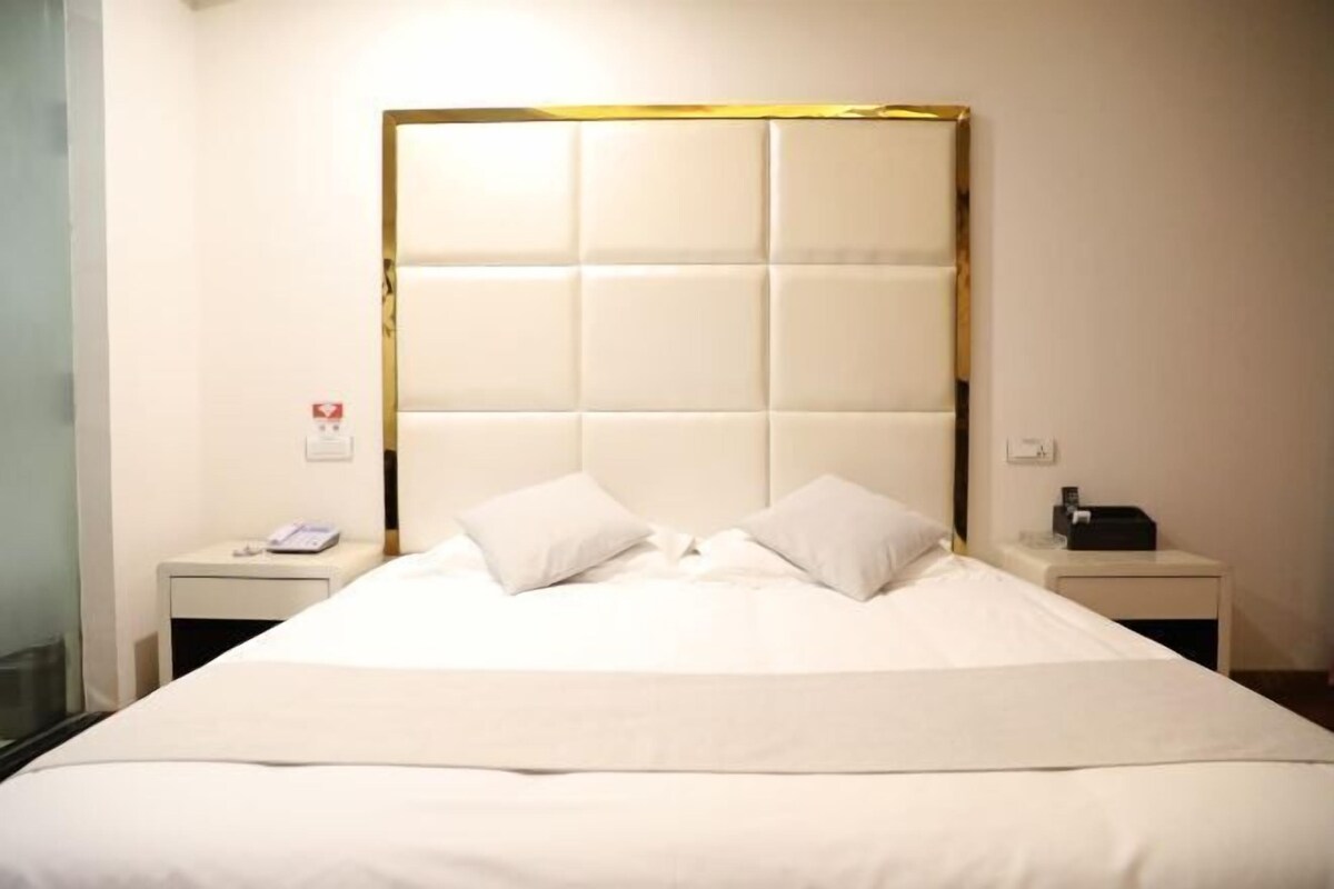 A hotel room with a large bed, two bedside tables, a phone, and a lamp.