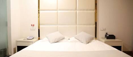 A hotel room with a large bed, two bedside tables, a phone, and a lamp.