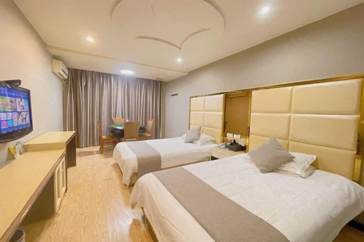 Habitación de hotel con dos camas, un escritorio, un televisor y una cortina.